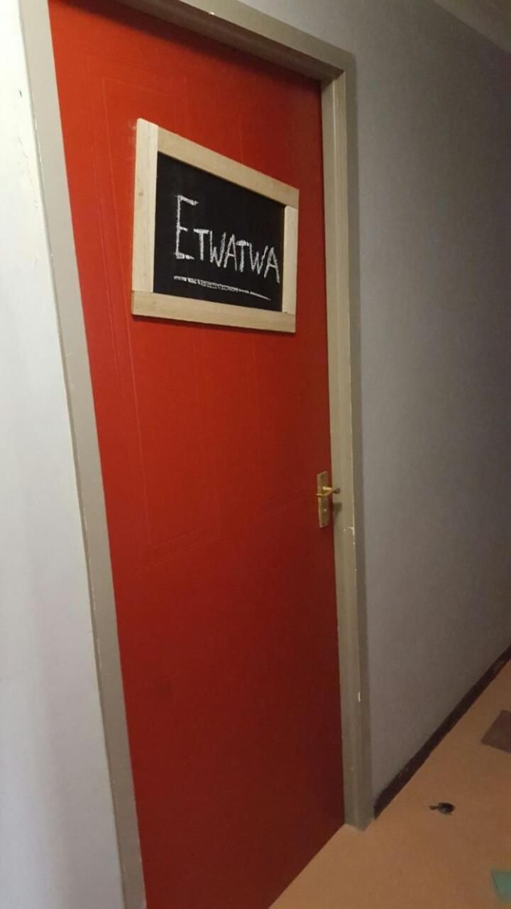 En rød dør med et skilt, der står 'ETWATWA', og et lille vindue over den.