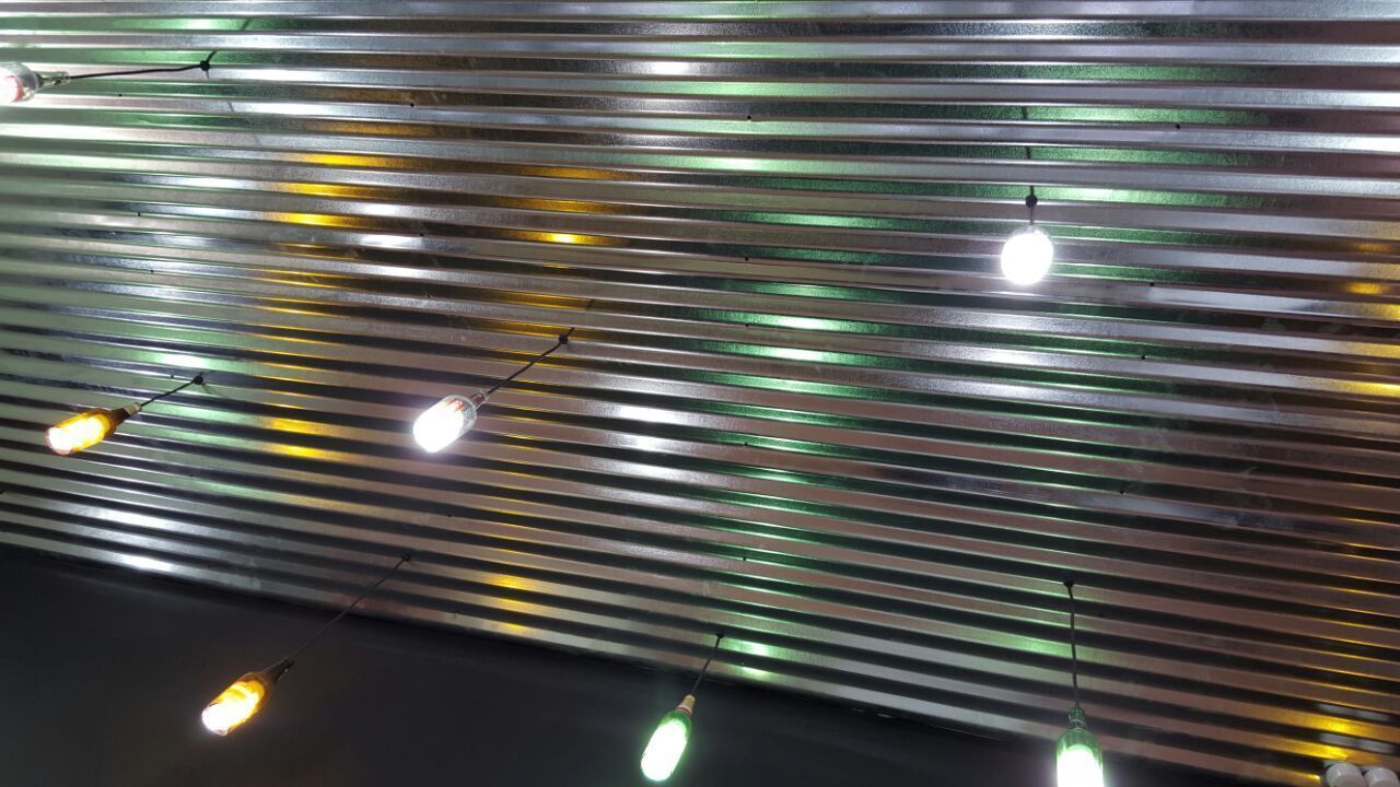 Teto com ripas metálicas horizontais e luminárias pendentes.