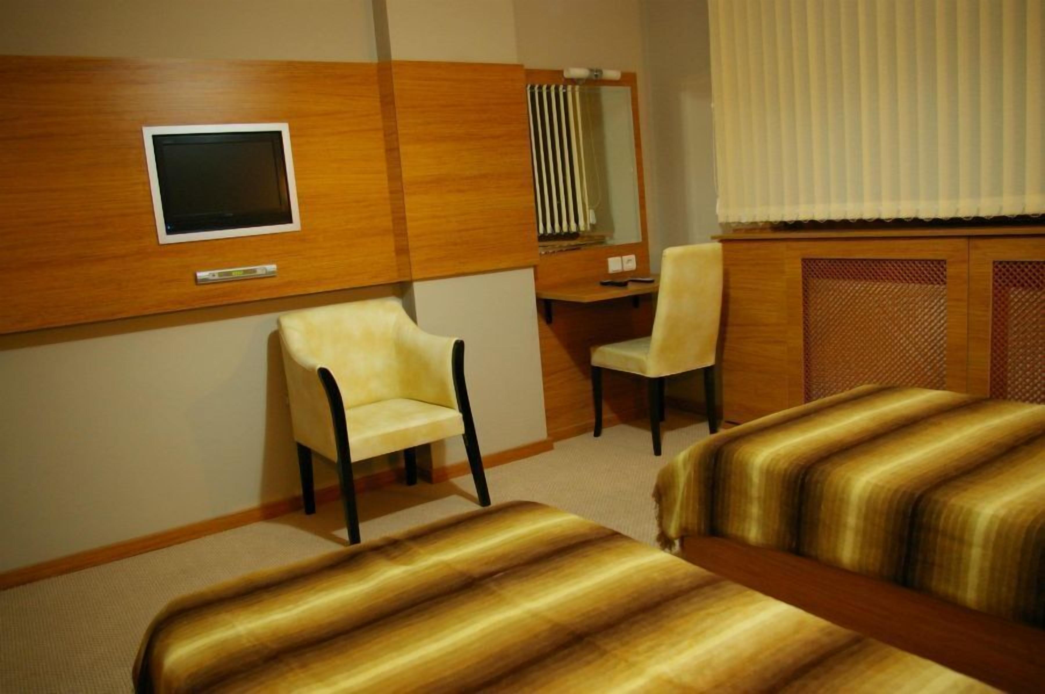 Une chambre d’hôtel avec deux lits, un bureau, une chaise, une télévision et un miroir.