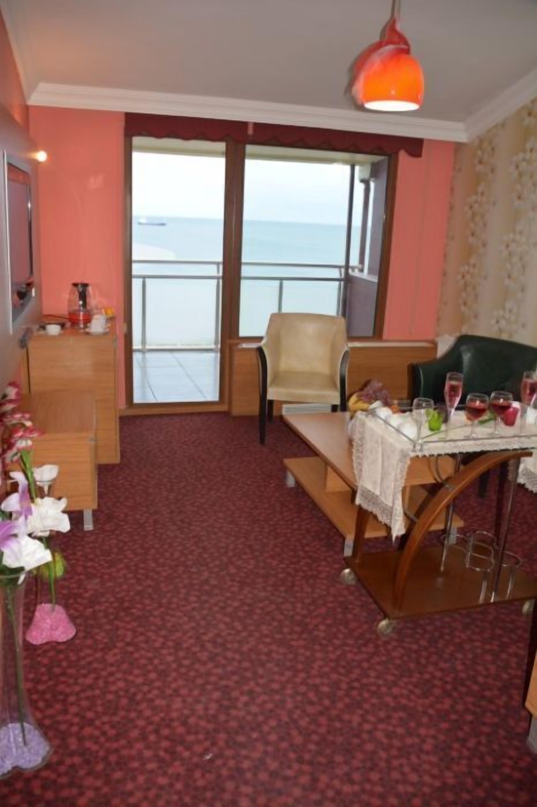 A room with a balcony, a table set with glasses, a vase with flowers, and a wooden dresser.