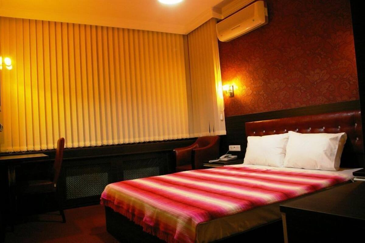 Une chambre d’hôtel équipée d’un lit, d’un bureau, d’une chaise et d’un téléphone fixé au mur.