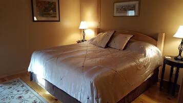 A neatly made bed with a beige duvet, two bedside lamps, and a framed picture on the wall.