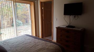 A bedroom with a bed, a dresser, and a television mounted on the wall.