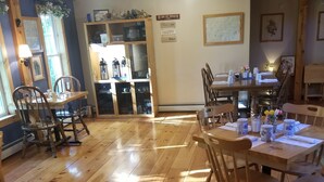 A wooden-floored dining area with tables and chairs, a kitchen area with cabinets and appliances, and a wall with a motivational quote. - Blueberry Fields B&B (Washington)