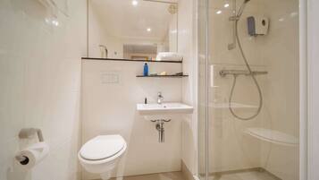 A modern bathroom with a toilet, sink, and glass-enclosed shower area.