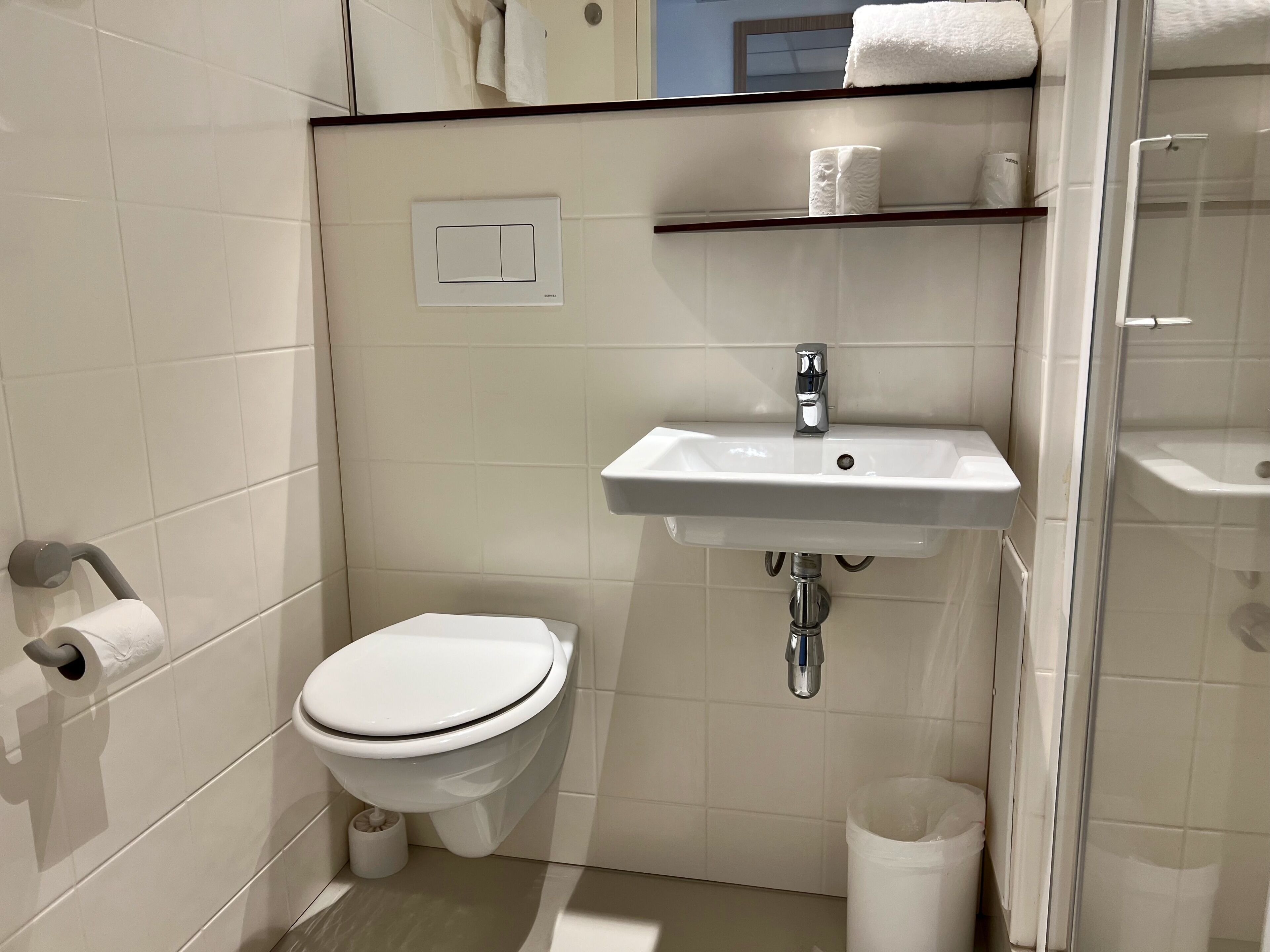 A small bathroom with a toilet, a sink, and a shower.