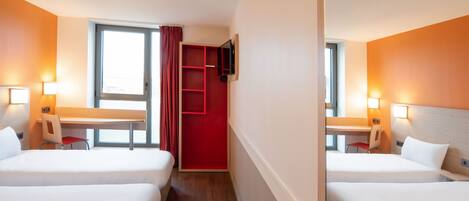 A hotel room with two beds, a desk, a chair, a TV mounted on the wall, and a window with curtains.