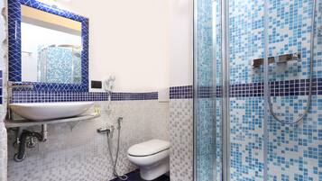 Une salle de bain avec un lavabo blanc, des toilettes et une douche aux carreaux de mosaïque bleus.