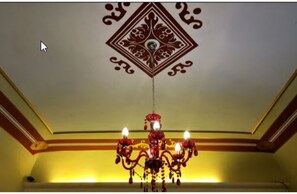 A chandelier with multiple lights hanging from a ceiling with a decorative diamond pattern. - Bienestar  Maison de Charme (Alghero)