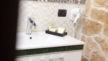 A bathroom with a white sink, a hairdryer, and a small shelf with toiletries.