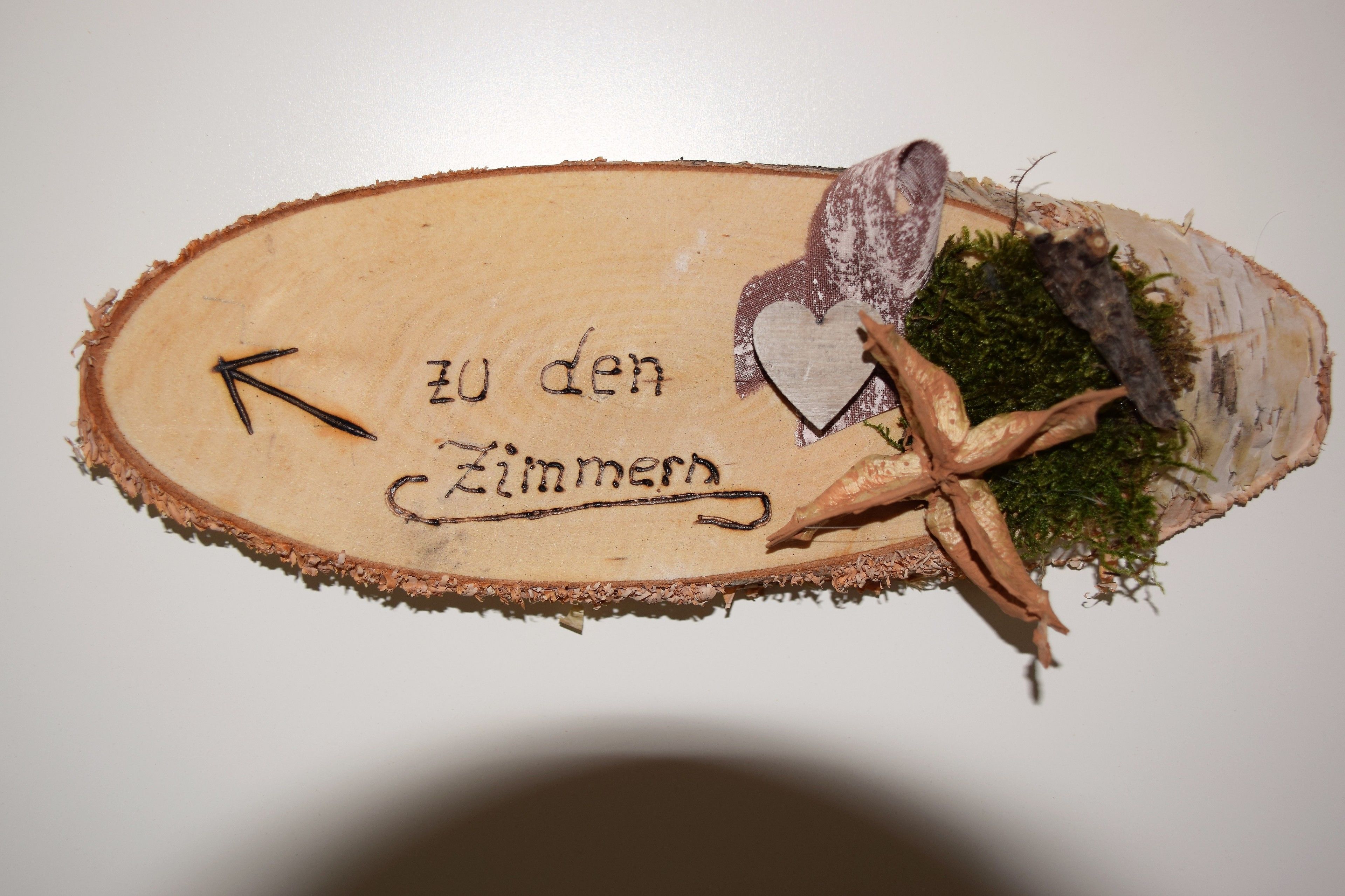 Un letrero de madera con el texto 'zu den Zimmern' y una flecha que apunta a la izquierda.