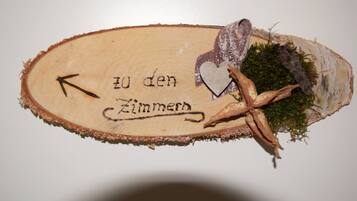 Un letrero de madera con el texto 'zu den Zimmern' y una flecha que apunta a la izquierda.
