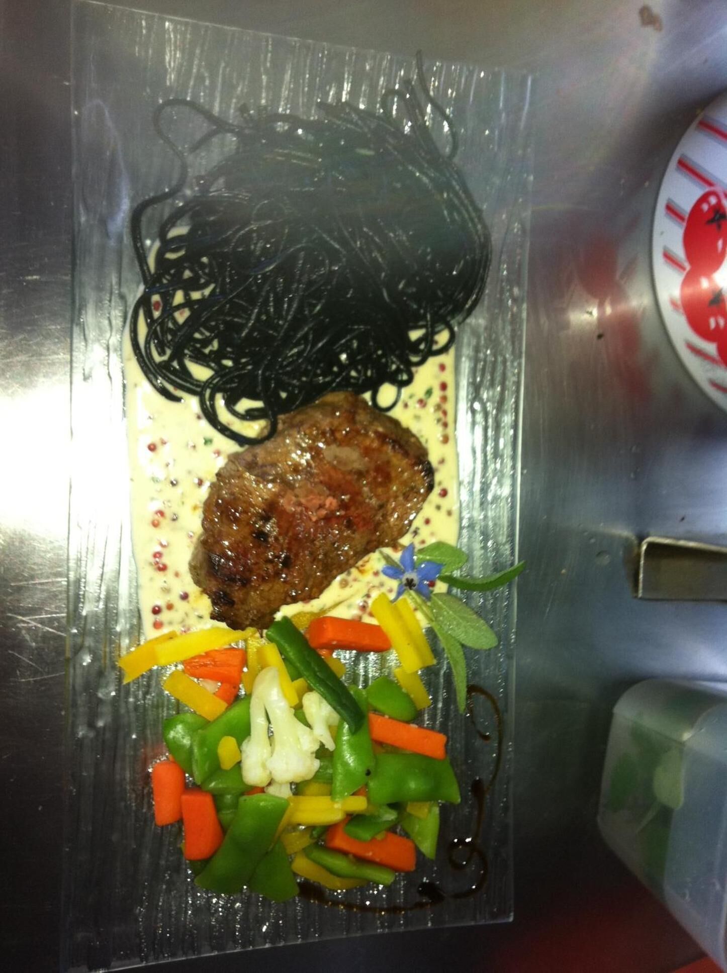 Un piatto con bistecca, verdure e noodles.
