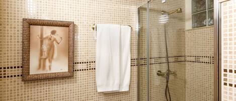 A bathroom with mosaic tile walls, a framed picture, and a shower with a glass door.
