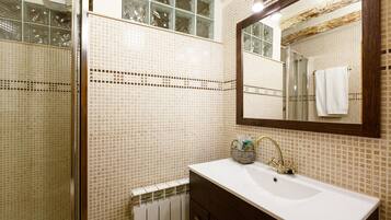 A bathroom with a white sink, a mirror, and a shower with glass doors.