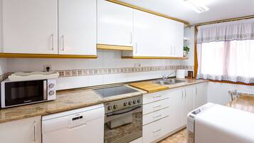 A modern kitchen with white cabinets, a microwave, a stove, and a dishwasher.