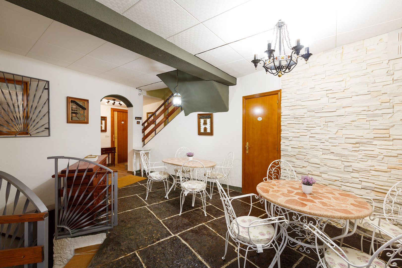 Un comedor con pared de piedra, una escalera y una araña.