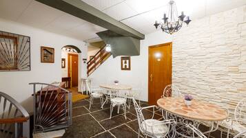 Un comedor con pared de piedra, una escalera y una araña.