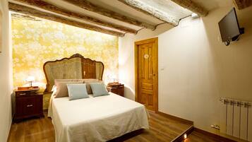 A bedroom with a wooden bed, a wooden door, a radiator, and a television on the wall.