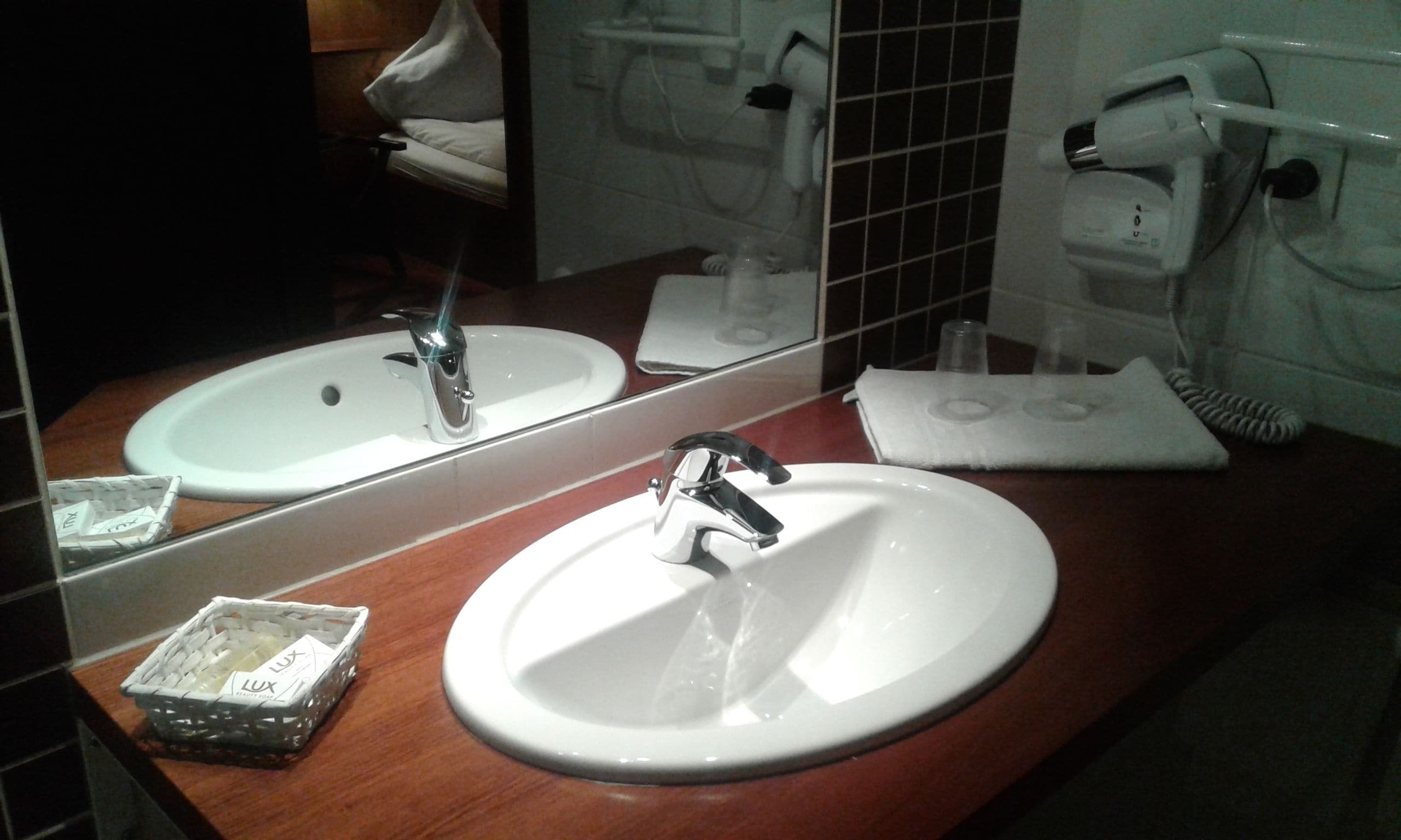 Un bagno con lavandino, specchio e portasciugamani.