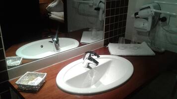 Un bagno con lavandino, specchio e portasciugamani.