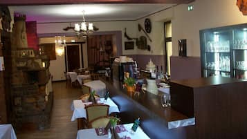 Een restaurant met een stenen openhaard, houten tafels en een bar.