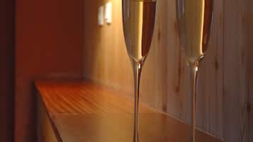 Dos copas de champán sobre una barra de madera con una lámpara de pared al fondo.