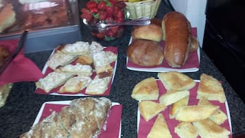 A buffet table with various baked goods and fruits.