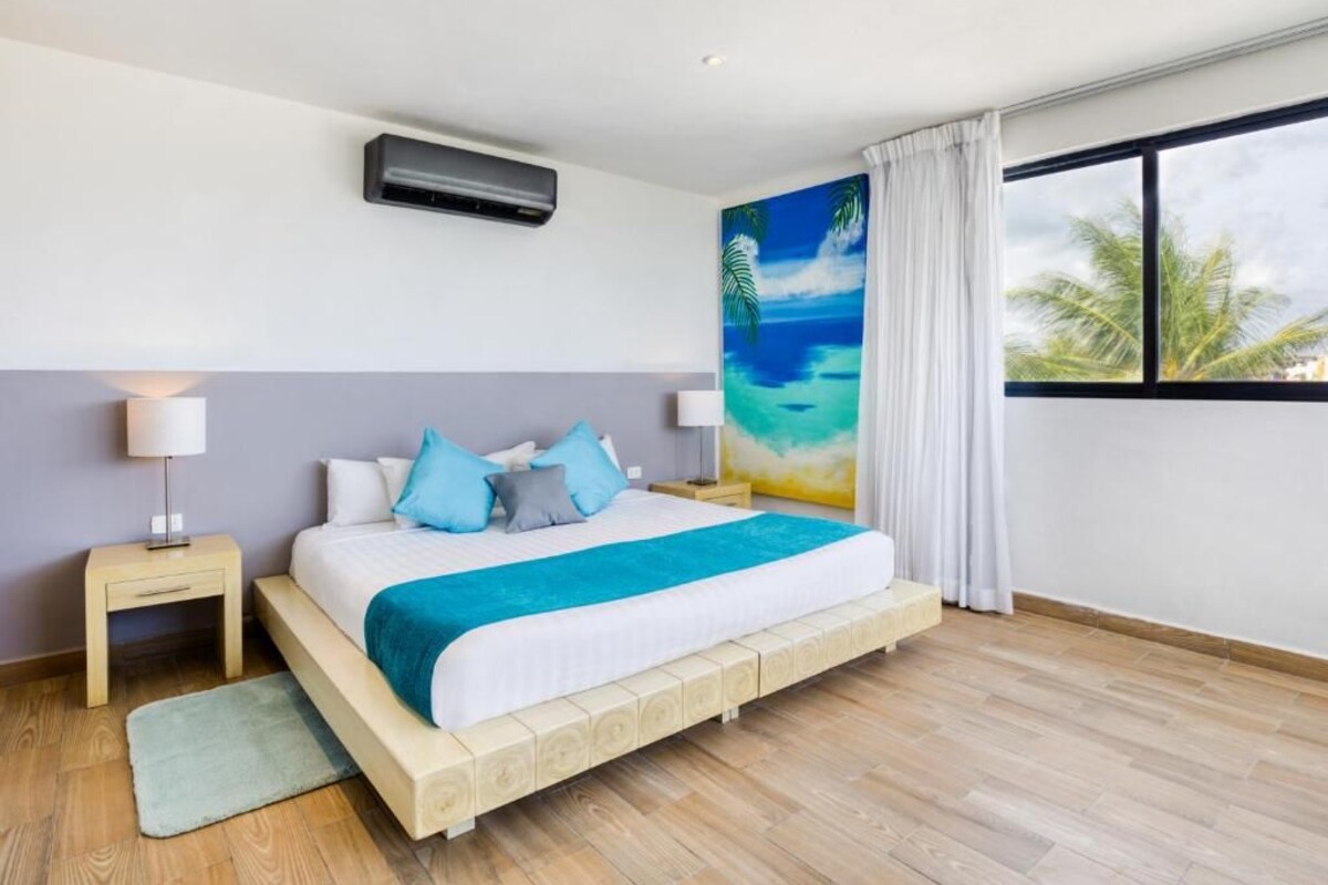 A bedroom with a bed, nightstands, a painting, and a window.