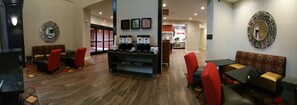 A modern cafe with a central counter, red chairs, and a coffee station. - Hampton Inn & Suites Houston/Atascocita (Humble)