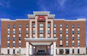 A modern hotel with a prominent sign reading "Hampton Inn & Suites." It features a symmetrical facade with multiple windows and a central entrance. - Hampton Inn & Suites Houston/Atascocita (Humble)