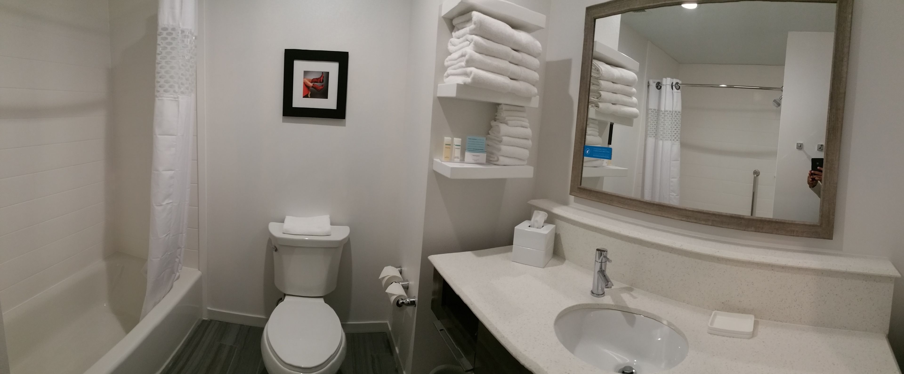 A modern bathroom with a toilet, sink, and a large mirror.