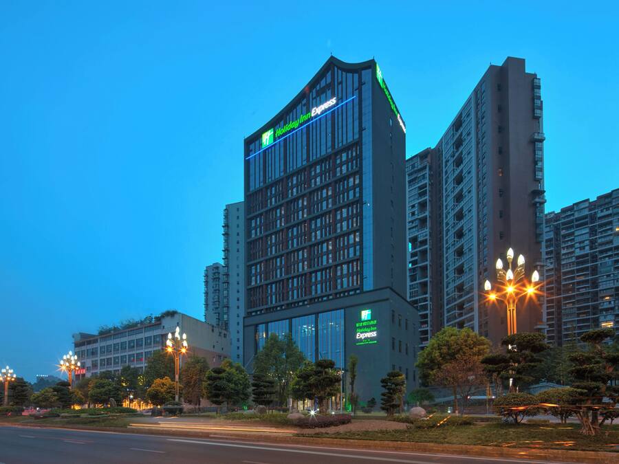 Un immeuble à plusieurs étages, sur lequel on peut voir une enseigne « Holiday Inn Express », entouré d’autres immeubles de grande hauteur et de lampadaires.