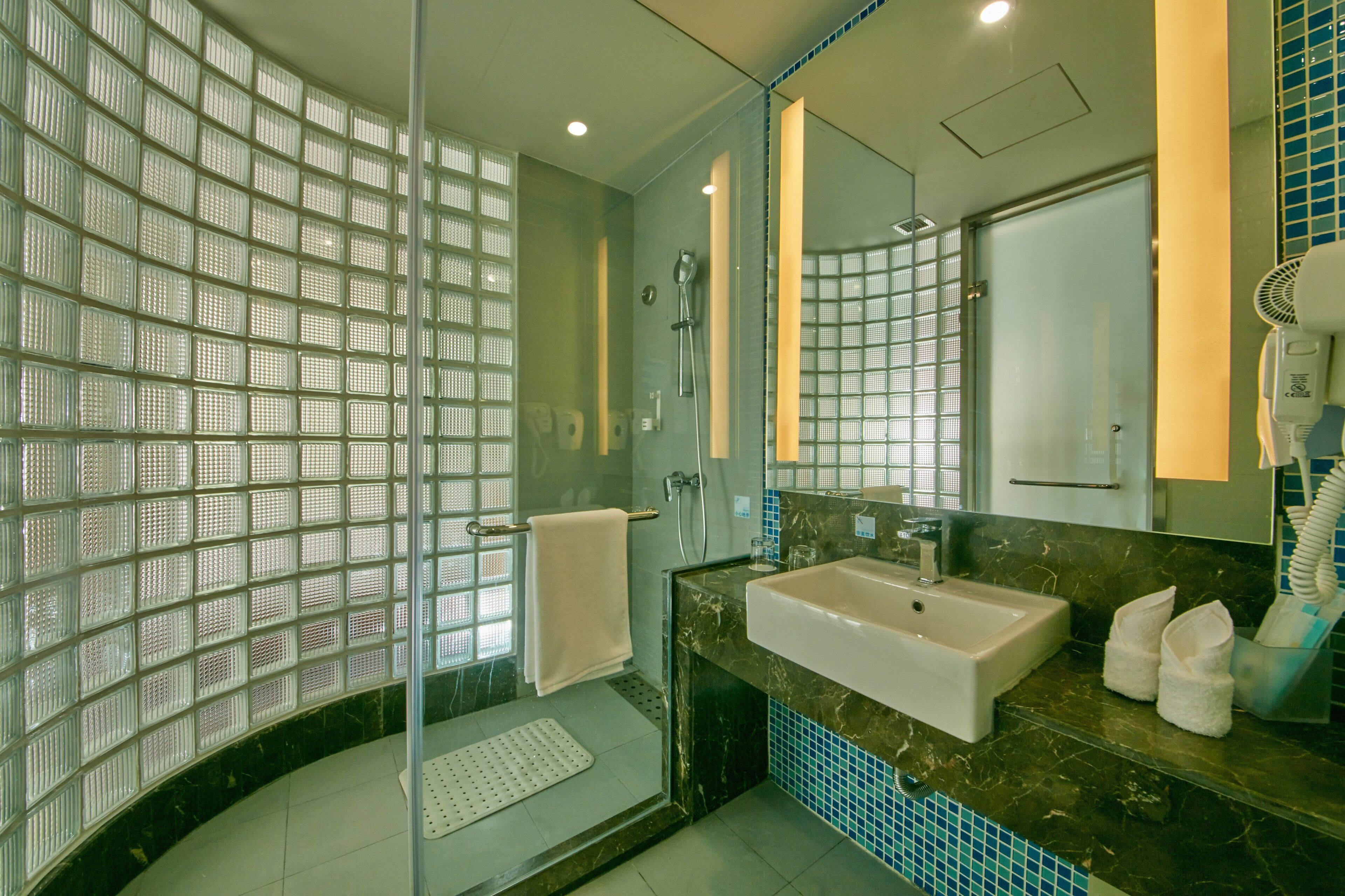 Un baño moderno con cabina de ducha de vidrio, lavamanos y espejo.