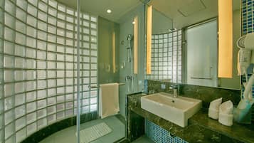 Un baño moderno con cabina de ducha de vidrio, lavamanos y espejo.