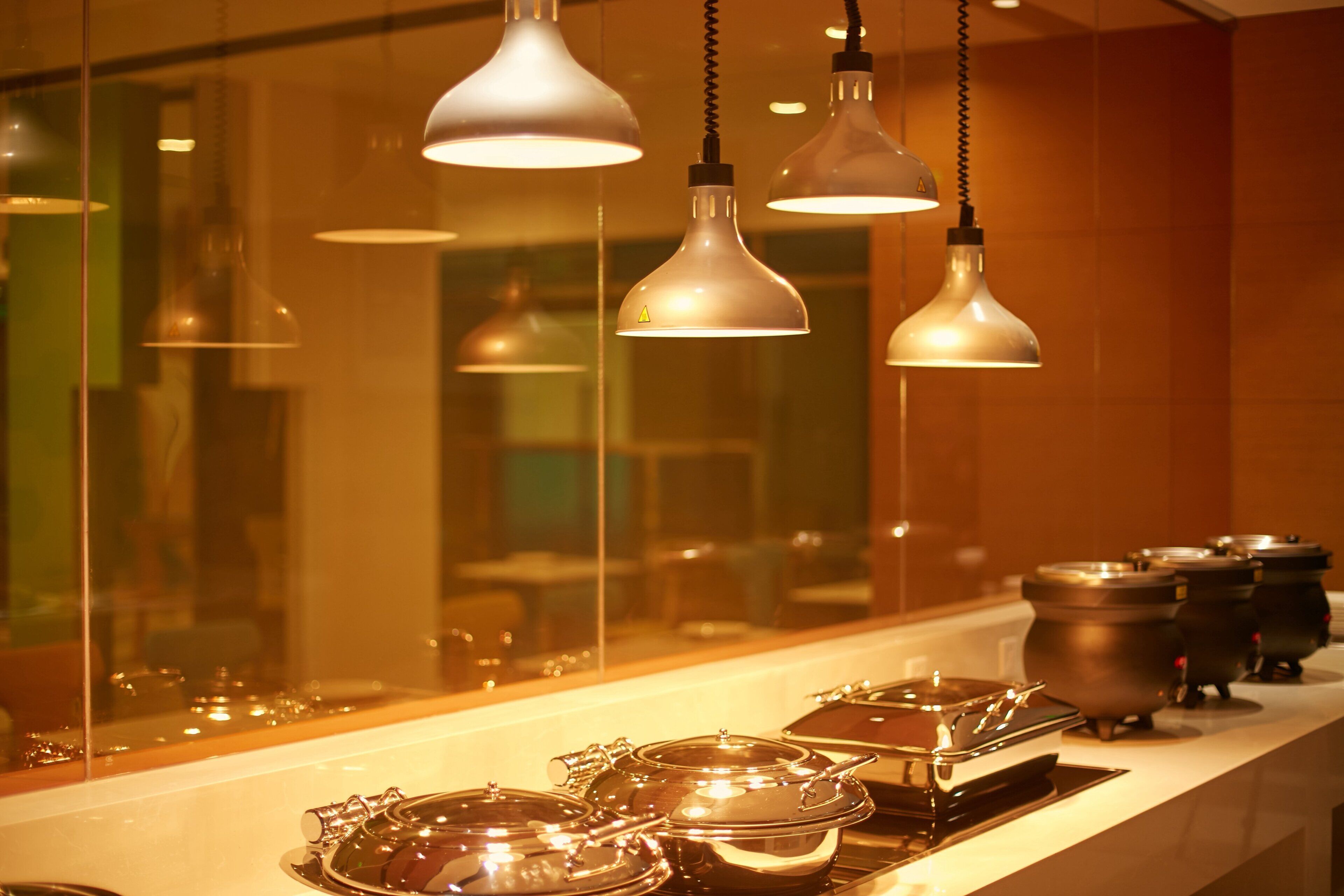 A kitchen area with hanging pendant lights and stainless steel cookware on the counter.