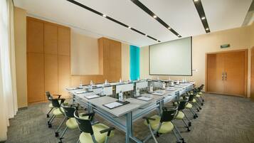 A conference room with a long table, chairs, and a projector screen.
