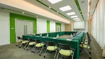 A conference room with a long table, chairs, and a projector screen.