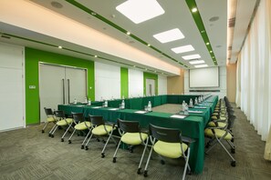 A conference room with a long table, chairs, and a projector screen. - Holiday Inn Express Leshan City Square by IHG (Leshan)