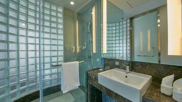 Un baño moderno con cabina de ducha de vidrio, un lavabo blanco y un espejo grande.