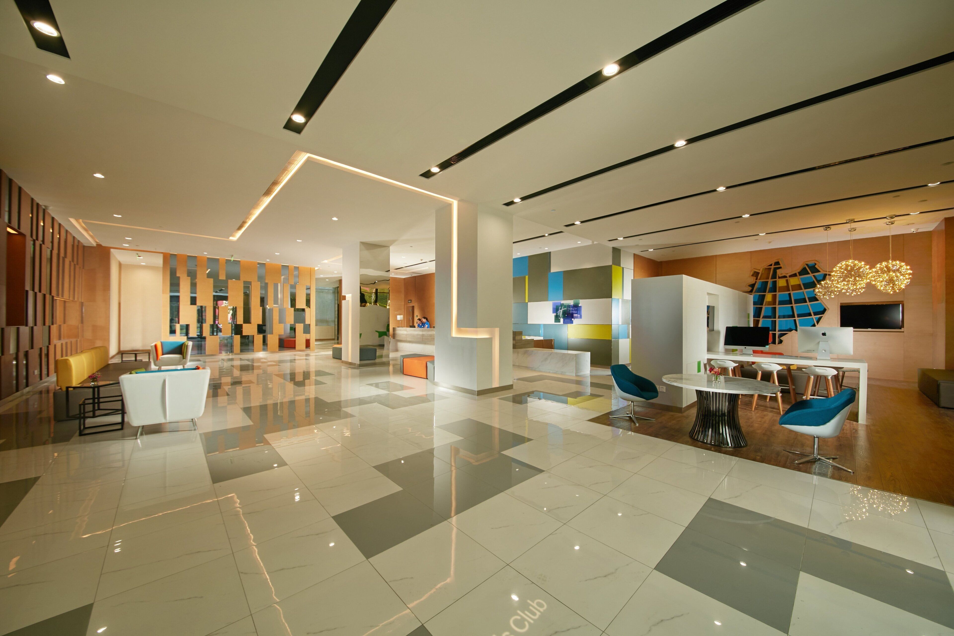 A modern hotel lobby with a clean, geometric floor pattern, a reception desk, and seating areas.