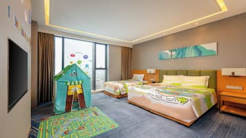 Habitación de hotel con dos camas, una tienda de juegos infantil, un tapete de juegos y un ventanal grande.