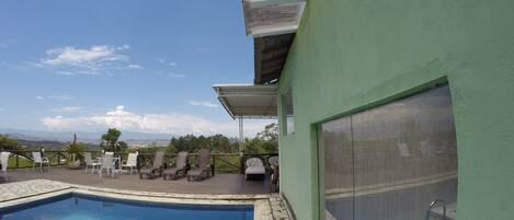 A pool area with lounge chairs and a view of the landscape.