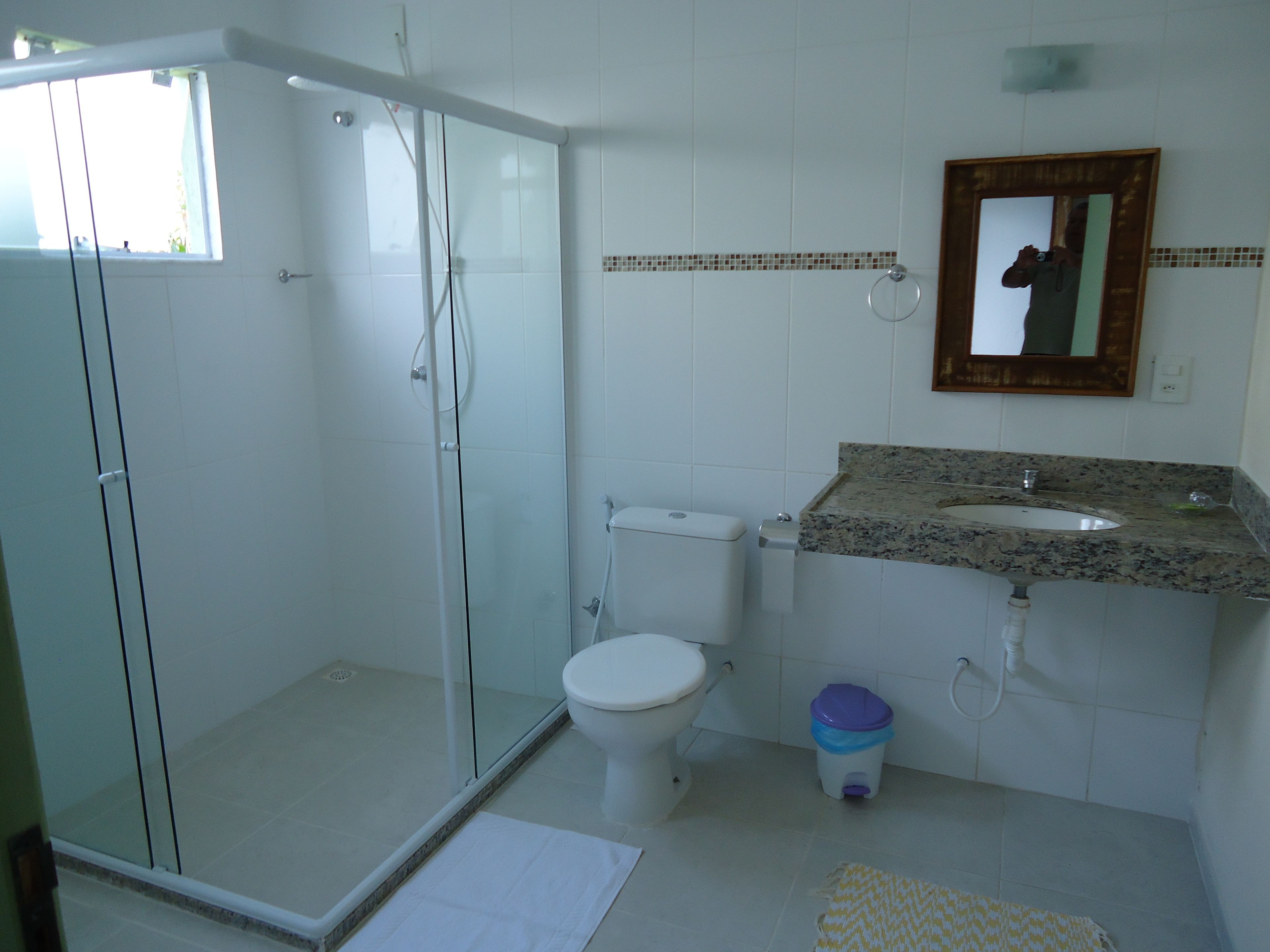 Une salle de bain dotée d’une douche à parois de verre, de toilettes, d’un lavabo avec un plan de travail en granit et d’un miroir au-dessus du lavabo.