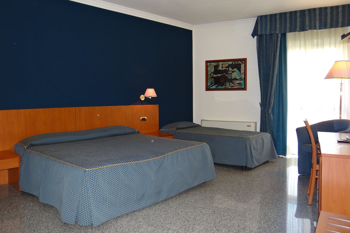 Comfort driepersoonskamer | Een minibar, een bureau, verduisterende gordijnen, babybedden