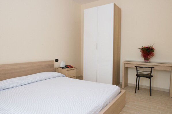 Una habitación de hotel con una cama, un escritorio, una silla, una mesita de noche y un teléfono.