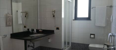 A bathroom with a sink, mirror, shower, and toilet.