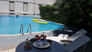 A swimming pool with a sun lounger and a table with drinks and snacks. - Hotel 90 (Capurso)