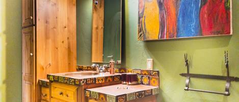 A bathroom with wooden cabinets, a sink with a decorative tile backsplash, a mirror, and a wall-mounted towel rack.