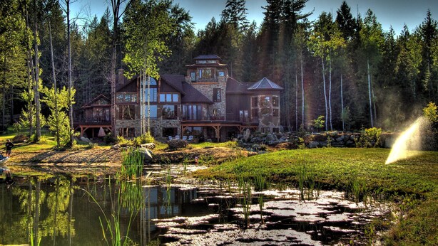 A large lodge with multiple buildings, a pond, and a forested area. - Talus Rock Retreat (Sandpoint)
